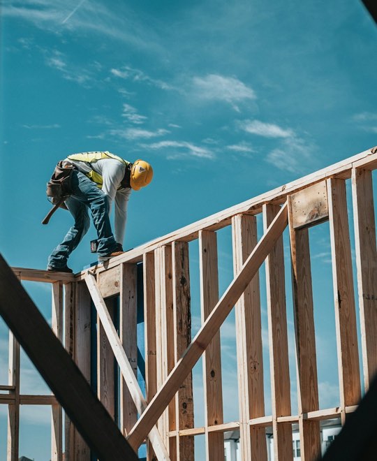 Worker on a wood frame against a blue sky