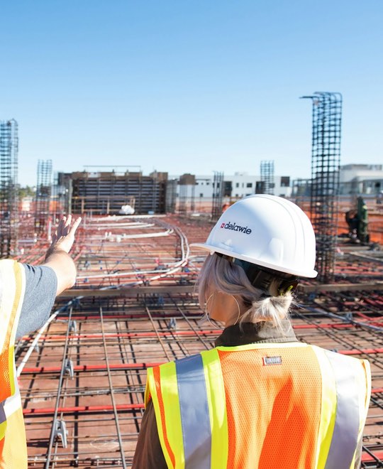 Two site supervisors in hard hats reviewing a large commercial site